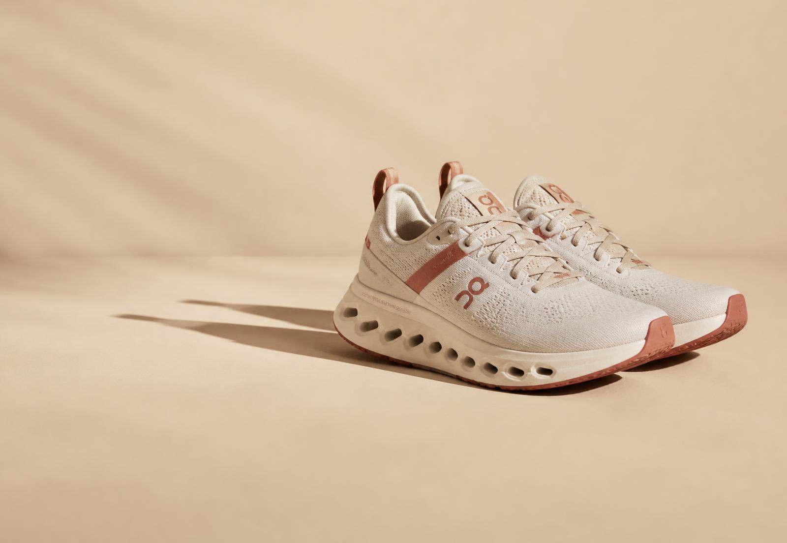 Pair of cream comfort sneakers on a warm sand backdrop